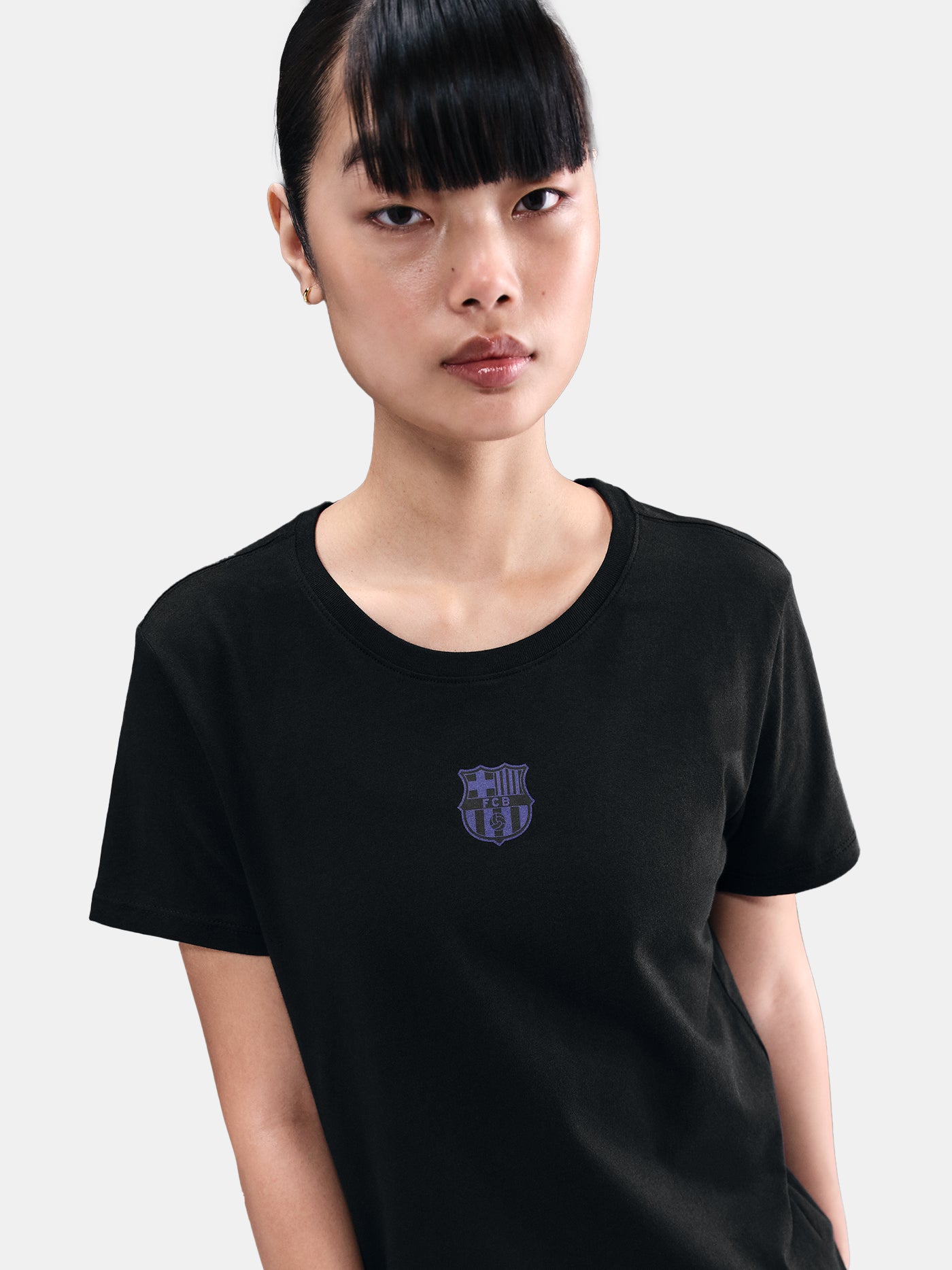 Black FC Barcelona Nike t-shirt with blue Barça crest on the chest, worn casually with blue pants and a black shoulder bag
