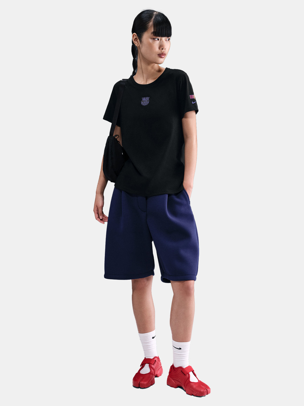 Black FC Barcelona Nike t-shirt with blue Barça crest on the chest, worn casually with blue pants and a black shoulder bag