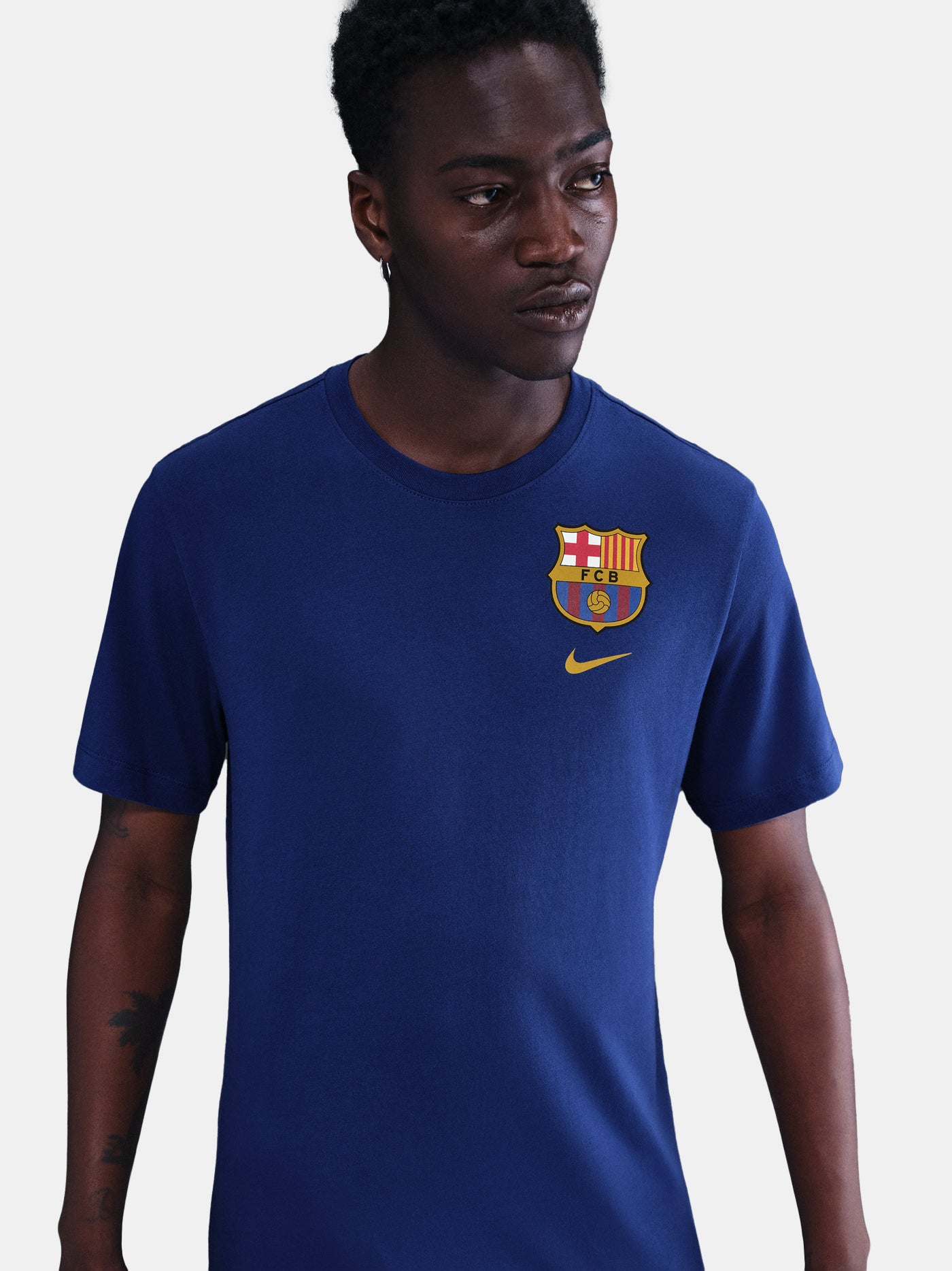 Blue Barça tee with yellow Nike logo, layered over white long sleeves and camo pants. Urban sporty style.
