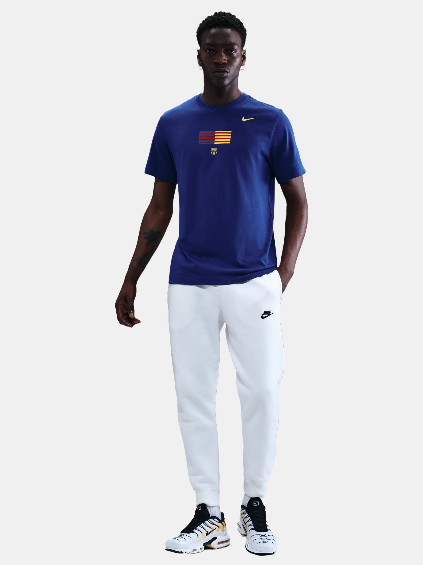 FC Barcelona men's t-shirt in royal blue featuring a minimalist front graphic with the Catalan and club colors, accompanied by the Nike Swoosh and Barça’s “Més que un club” symbol underneath. The design offers a clean and athletic streetwear look, perfect for everyday wear or matchday style.
