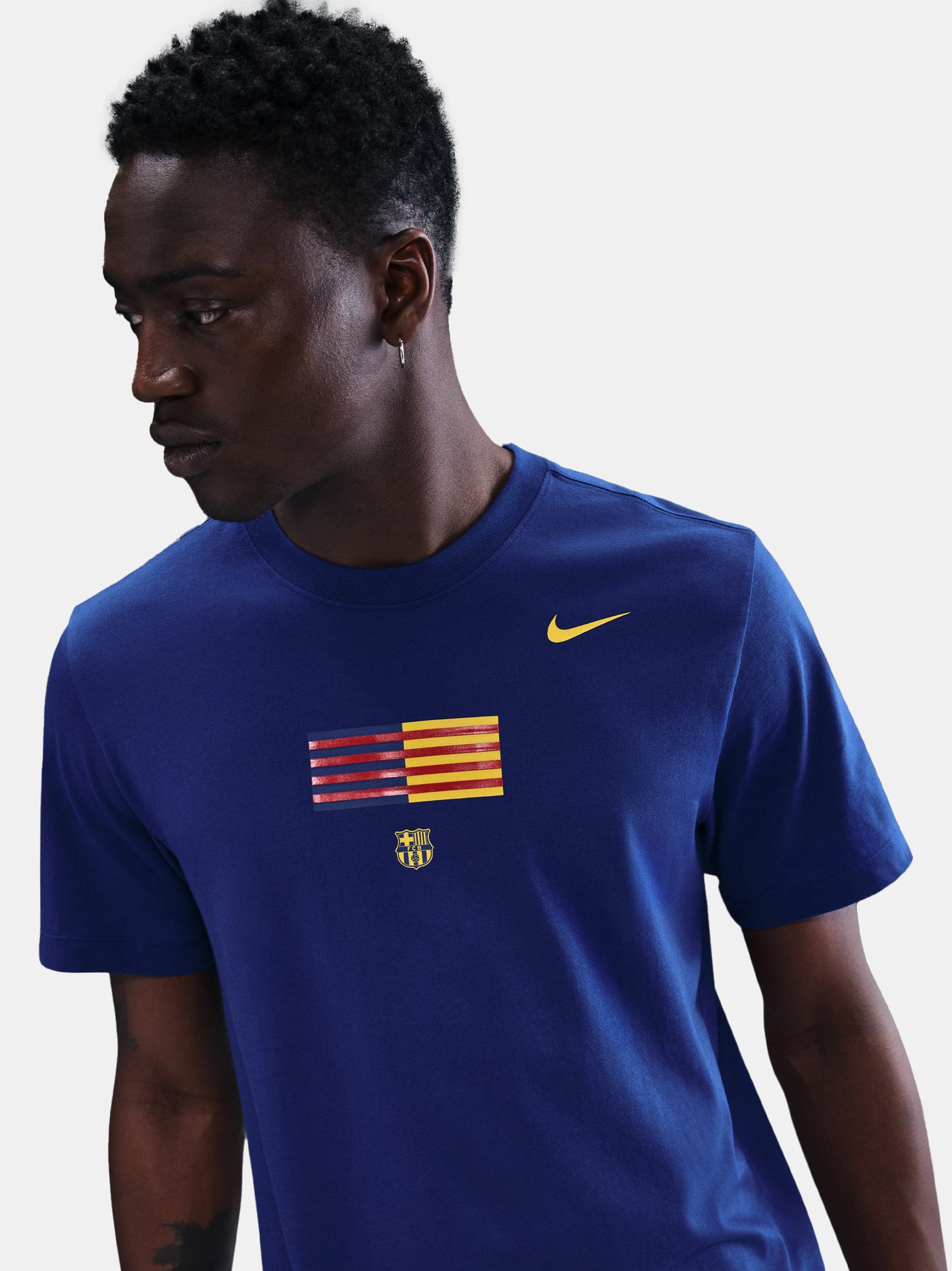 FC Barcelona men's t-shirt in royal blue featuring a minimalist front graphic with the Catalan and club colors, accompanied by the Nike Swoosh and Barça’s “Més que un club” symbol underneath. The design offers a clean and athletic streetwear look, perfect for everyday wear or matchday style.
