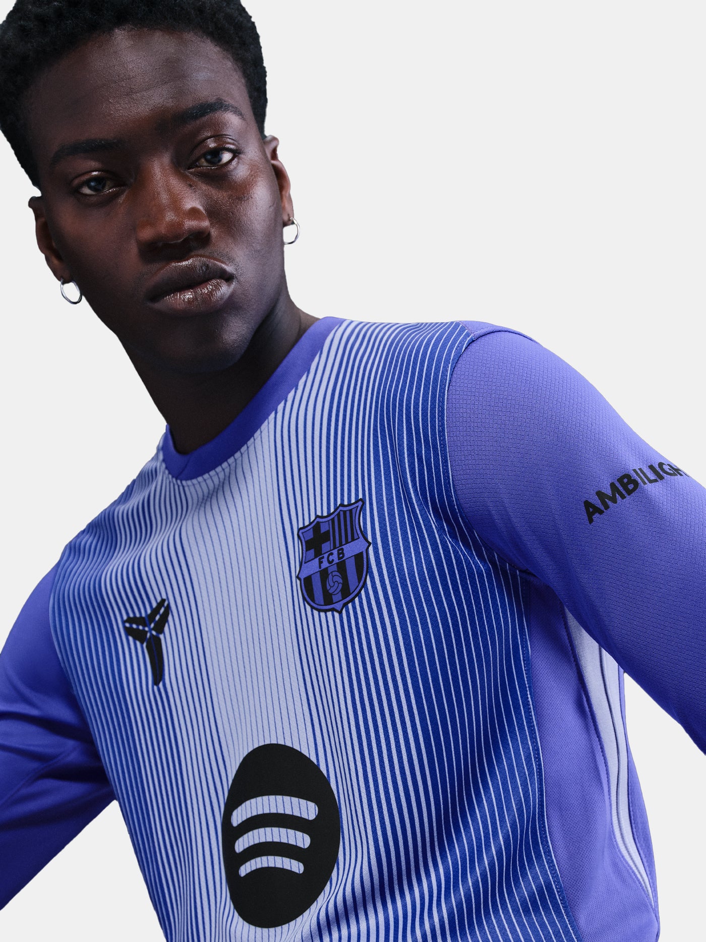 FC Barcelona away jersey in white with vertical blue stripes, purple sleeves, and black details, featuring the Barça crest, Nike logo, Spotify sponsor, and AMBILIGHT branding on the sleeve