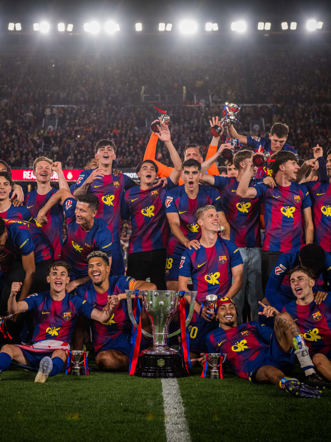 Soccer players celebrating with trophies on a field at night