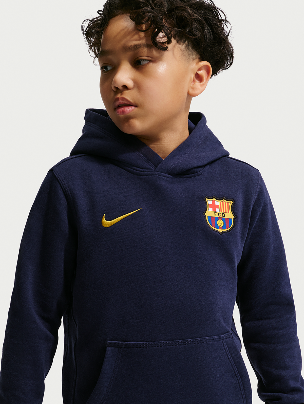 Front view of a navy FC Barcelona hoodie worn by a child, with a gold Nike swoosh and club crest on the chest.