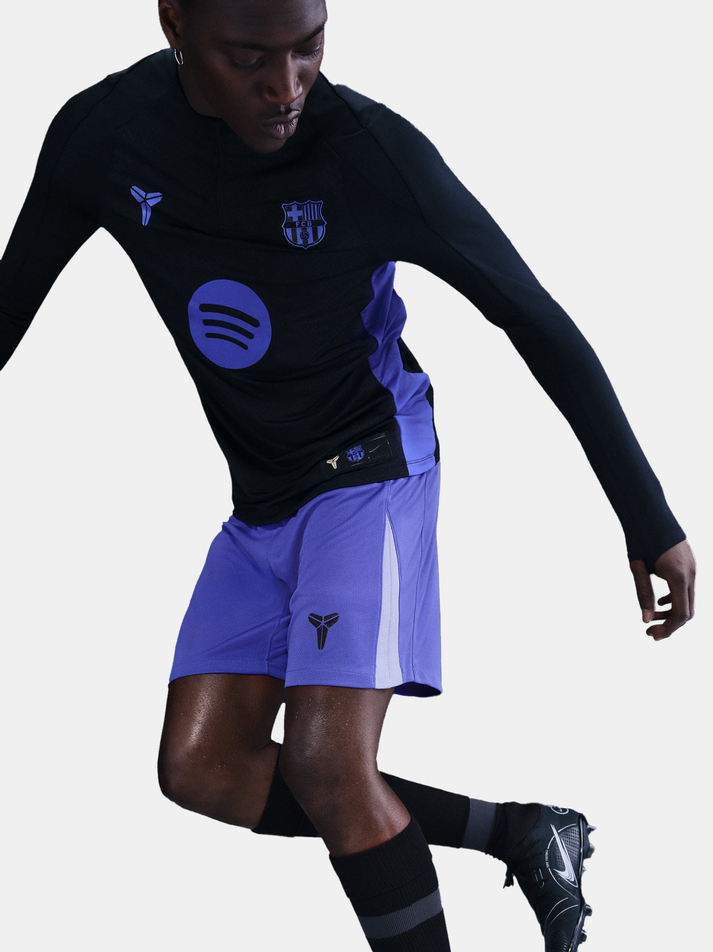 Person wearing a black long-sleeve top and purple shorts with visible branding.