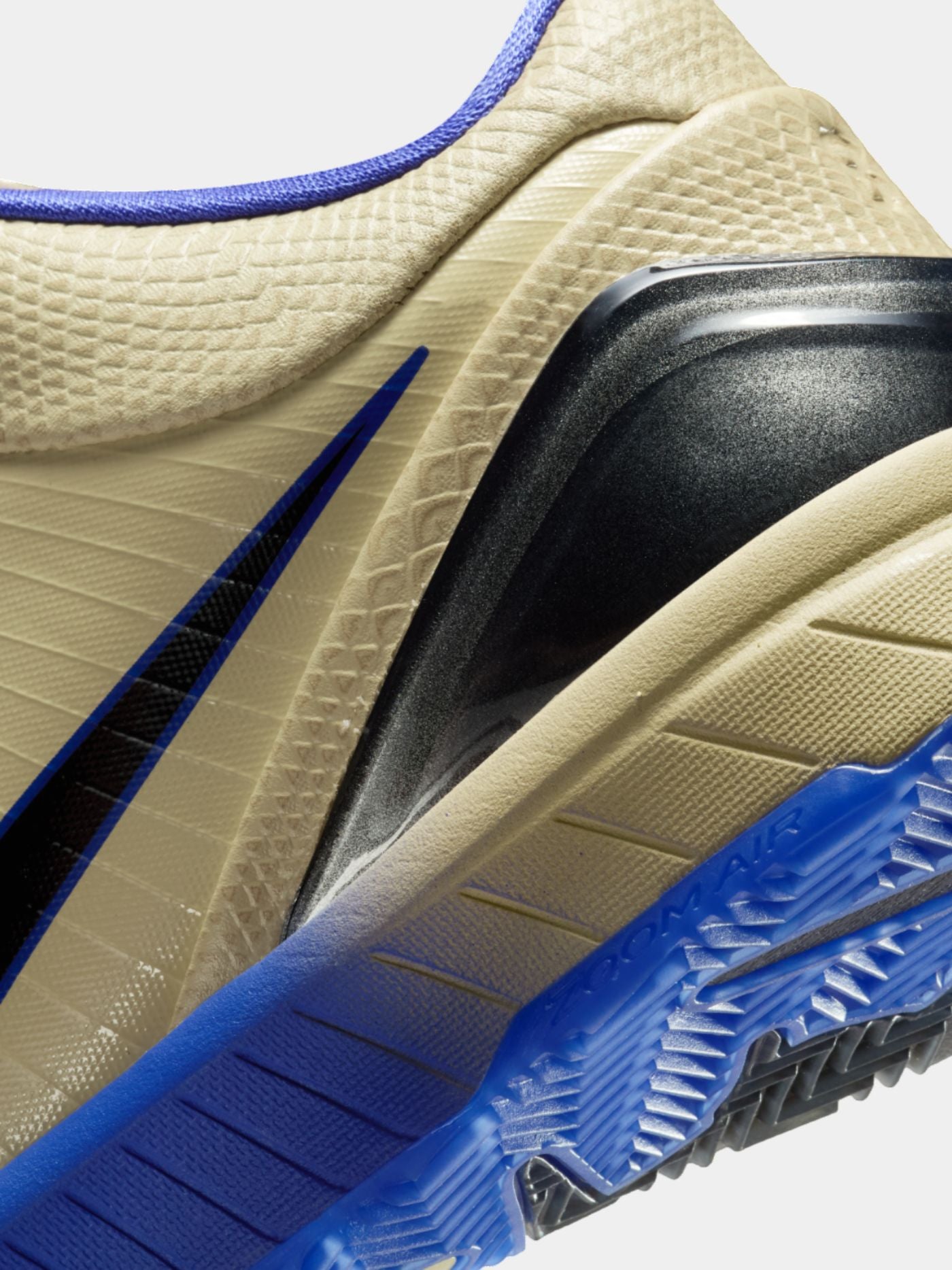 Close-up of a sneaker with beige, blue, and black details on a white background