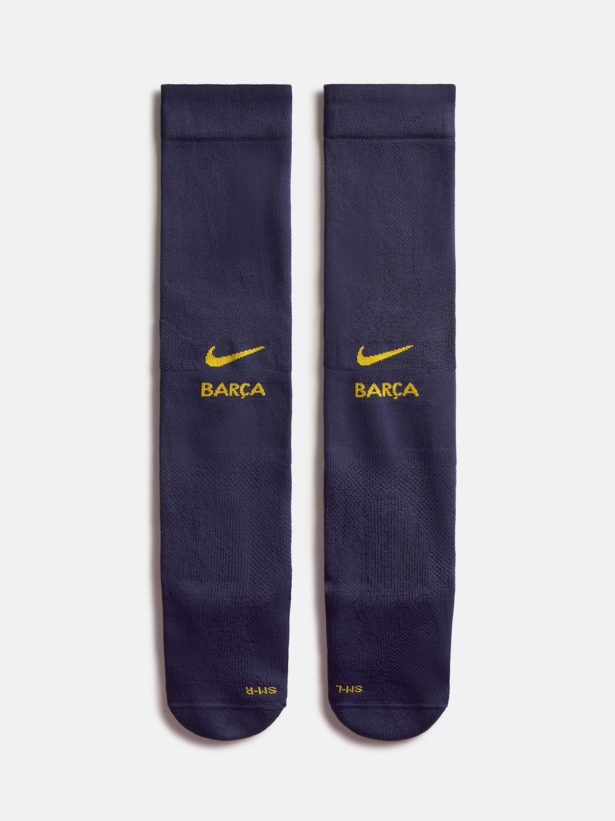 Parell de mitjons blau marí del FC Barcelona amb el swoosh groc de Nike i el logotip de BARÇA, mostrats un al costat de l’altre sobre fons blanc.
