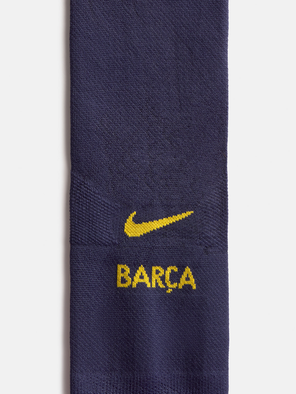 Primer pla d’un mitjó blau marí de FC Barcelona amb el swoosh groc de Nike i el text BARCA.