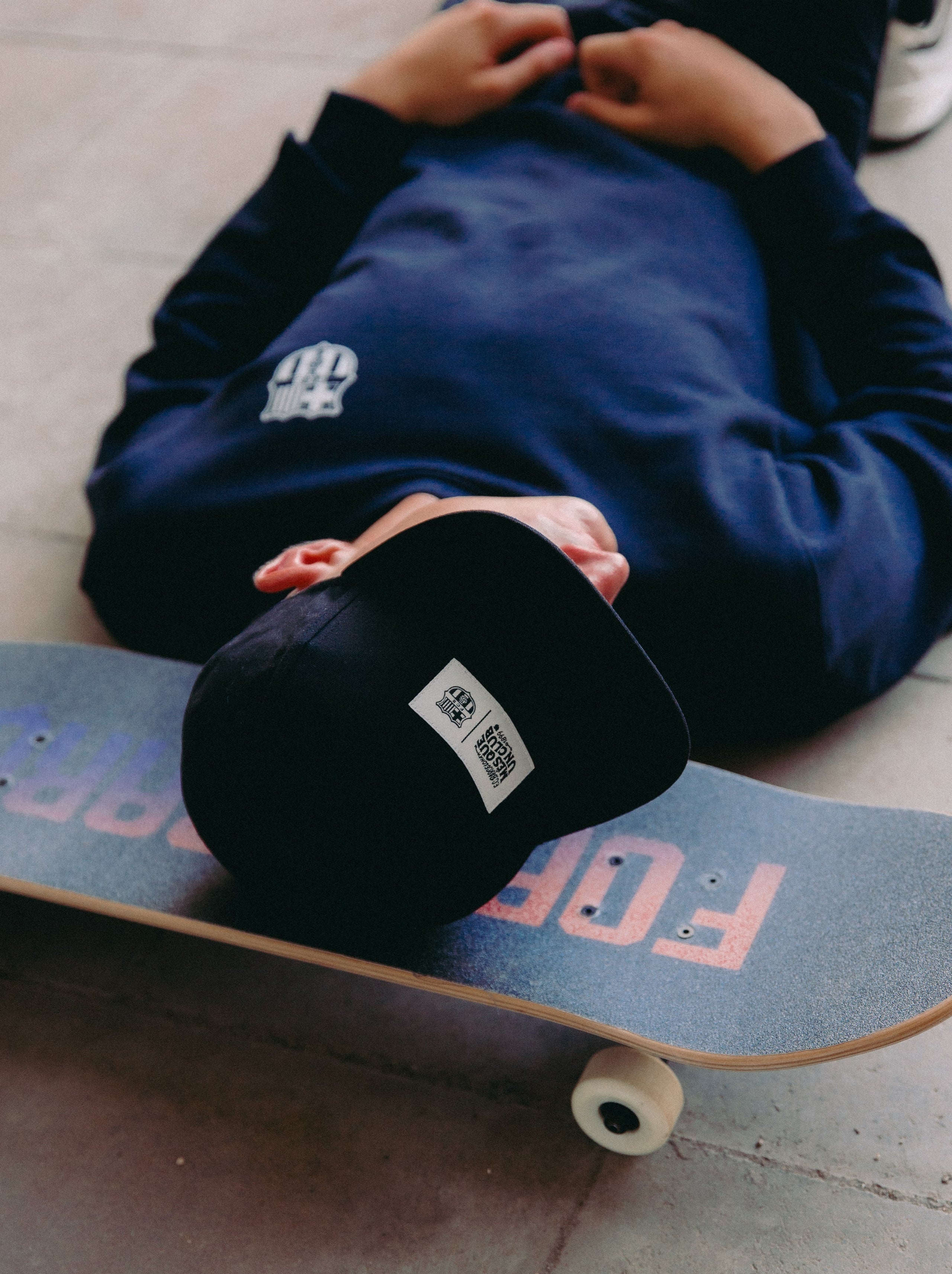 Black flat-brim cap featuring a rectangular white patch on the front with the FC Barcelona crest and the slogan "Més que un club" printed in black.