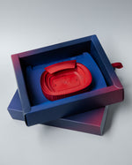 Red 3D miniature model of FC Barcelona’s Camp Nou stadium, placed on a blue surface. The model features detailed tiers, seating sections, and architectural elements of the iconic venue
