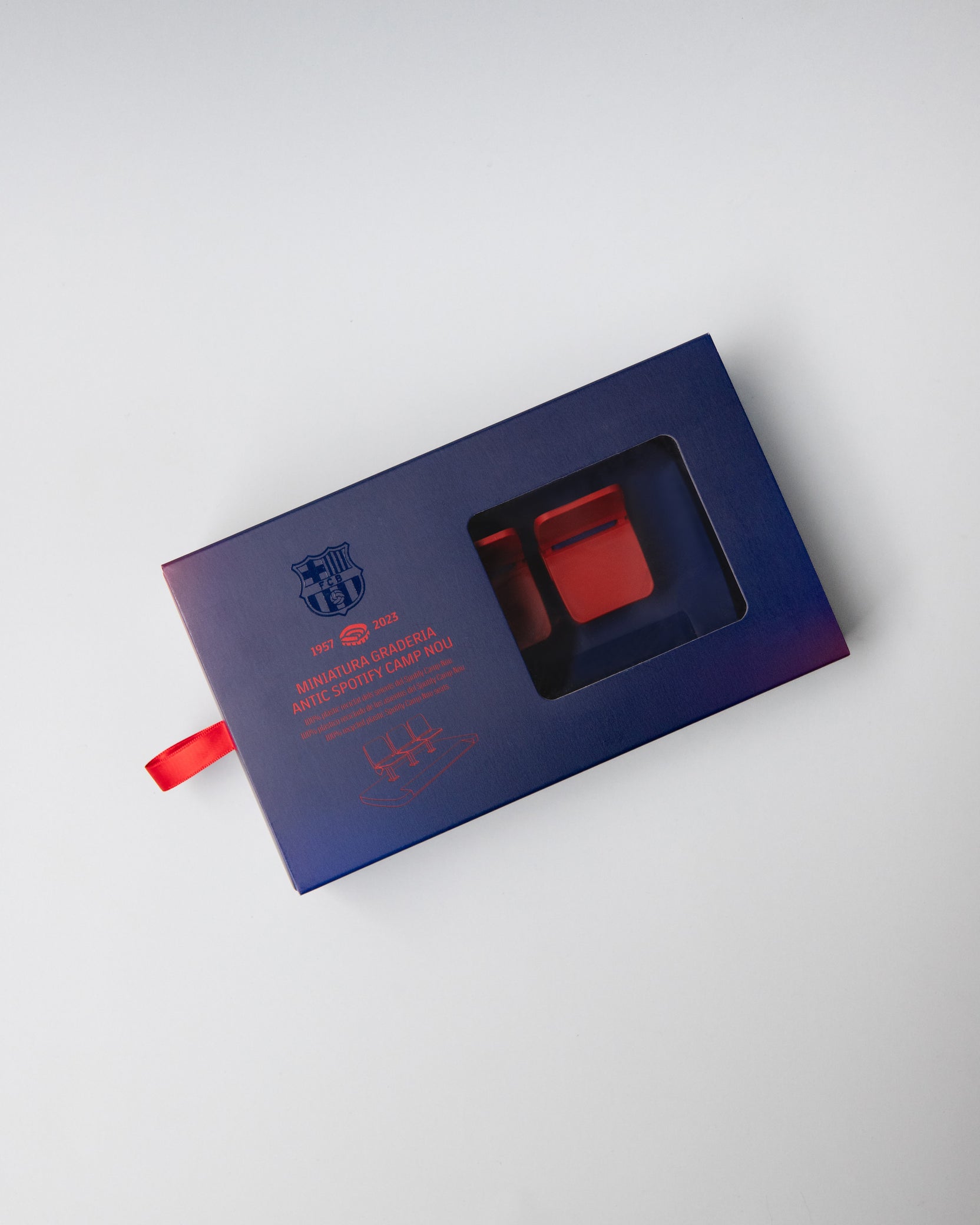 Miniature display of three iconic red Camp Nou stadium seats mounted on a blue base, commemorating the years 1957–2023, marking the historical timeline of FC Barcelona’s legendary stadium.