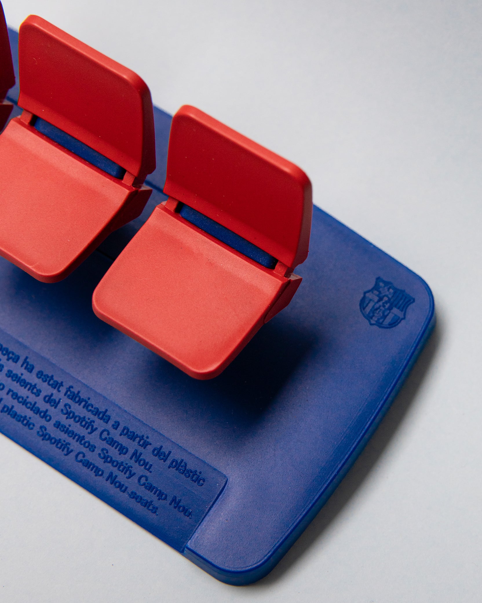 Miniature display of three iconic red Camp Nou stadium seats mounted on a blue base, commemorating the years 1957–2023, marking the historical timeline of FC Barcelona’s legendary stadium.