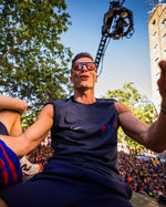 Man in sports jersey surrounded by people with a cityscape in the background