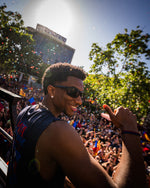 Man in sunglasses giving a thumbs up in front of a crowd with confetti