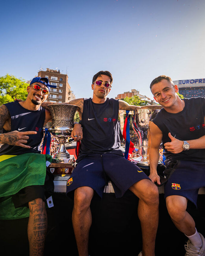 Three men sitting on a stage with trophies in front of a crowd