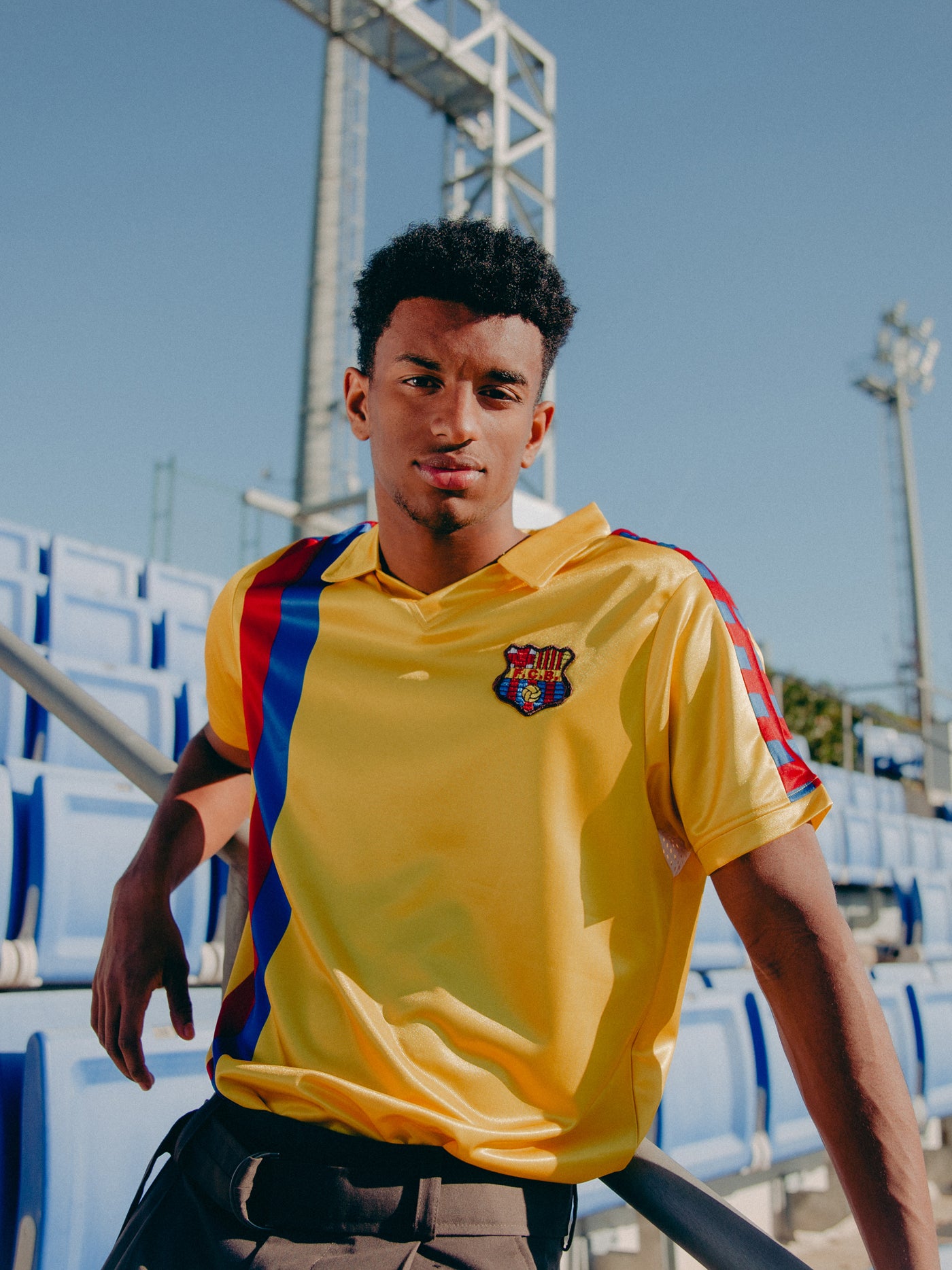 Yellow short-sleeve polo shirt with FC Barcelona crest and vertical red and blue stripe design.