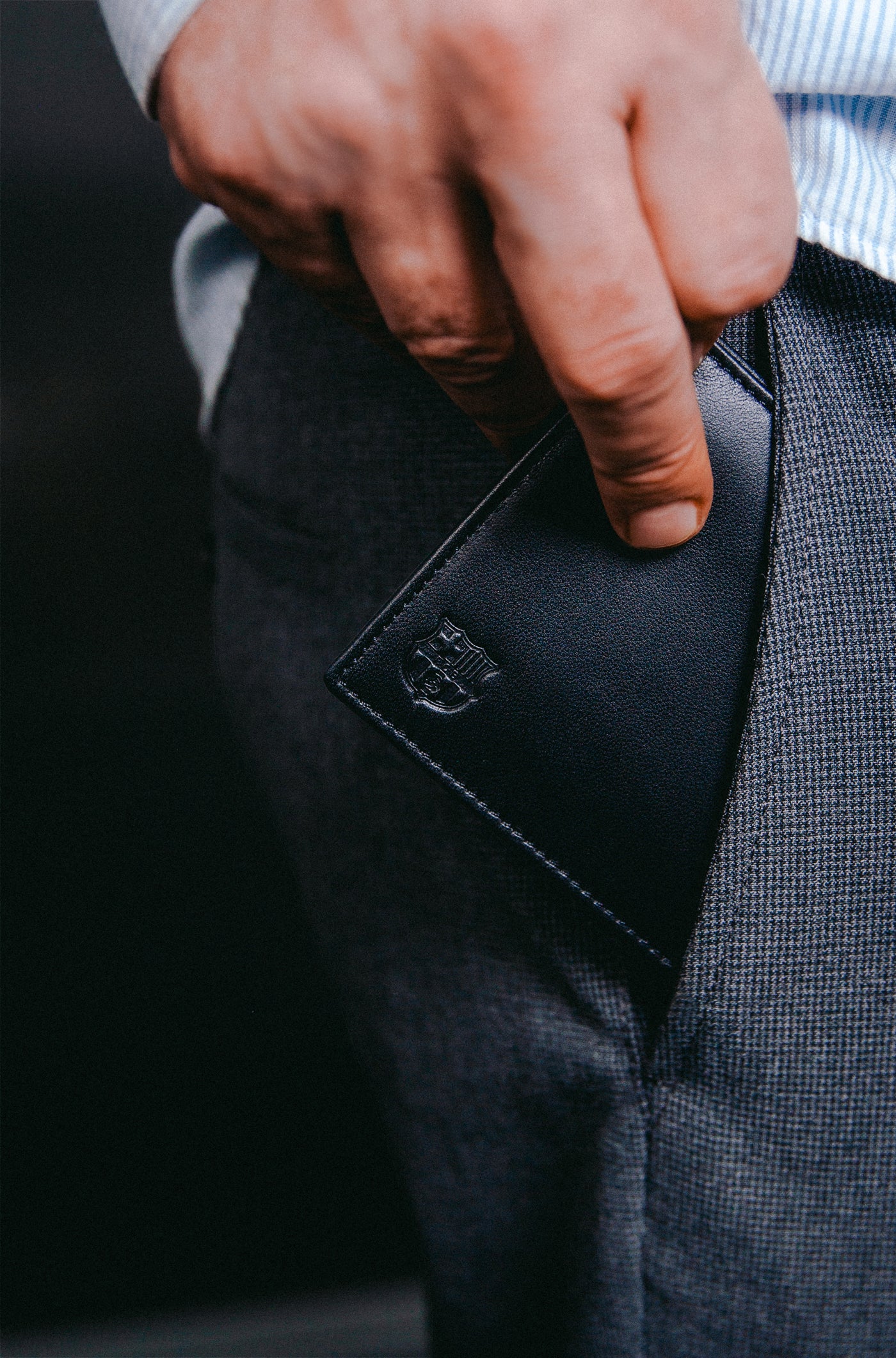 Close-up of a black leather wallet with an embossed FC Barcelona logo on the corner.
