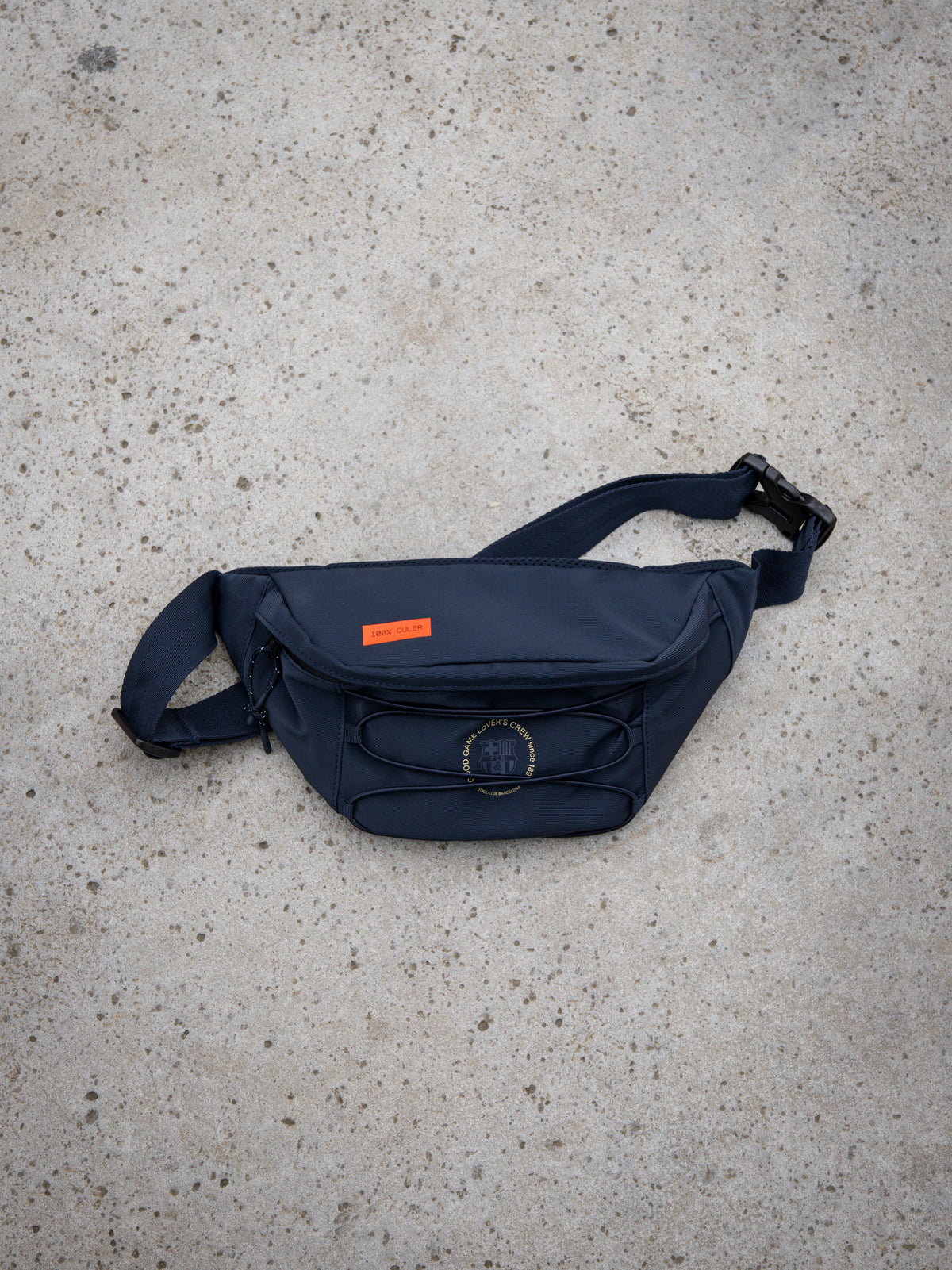 Navy blue FC Barcelona waist bag with adjustable strap, front pocket, circular crest detail, and orange label
