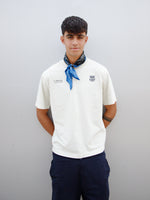 Marc Bernal wearing an off-white FC Barcelona T-shirt with tonal club crest and date detail on the chest, paired with a blue and black patterned neck scarf