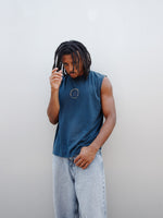 Jules Kounde wearing a sleeveless dark blue FC Barcelona T-shirt with circular crest print on the chest, paired with light denim jeans