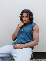 Jules Kounde wearing a sleeveless dark blue FC Barcelona T-shirt with circular crest print on the chest, paired with light denim jeans