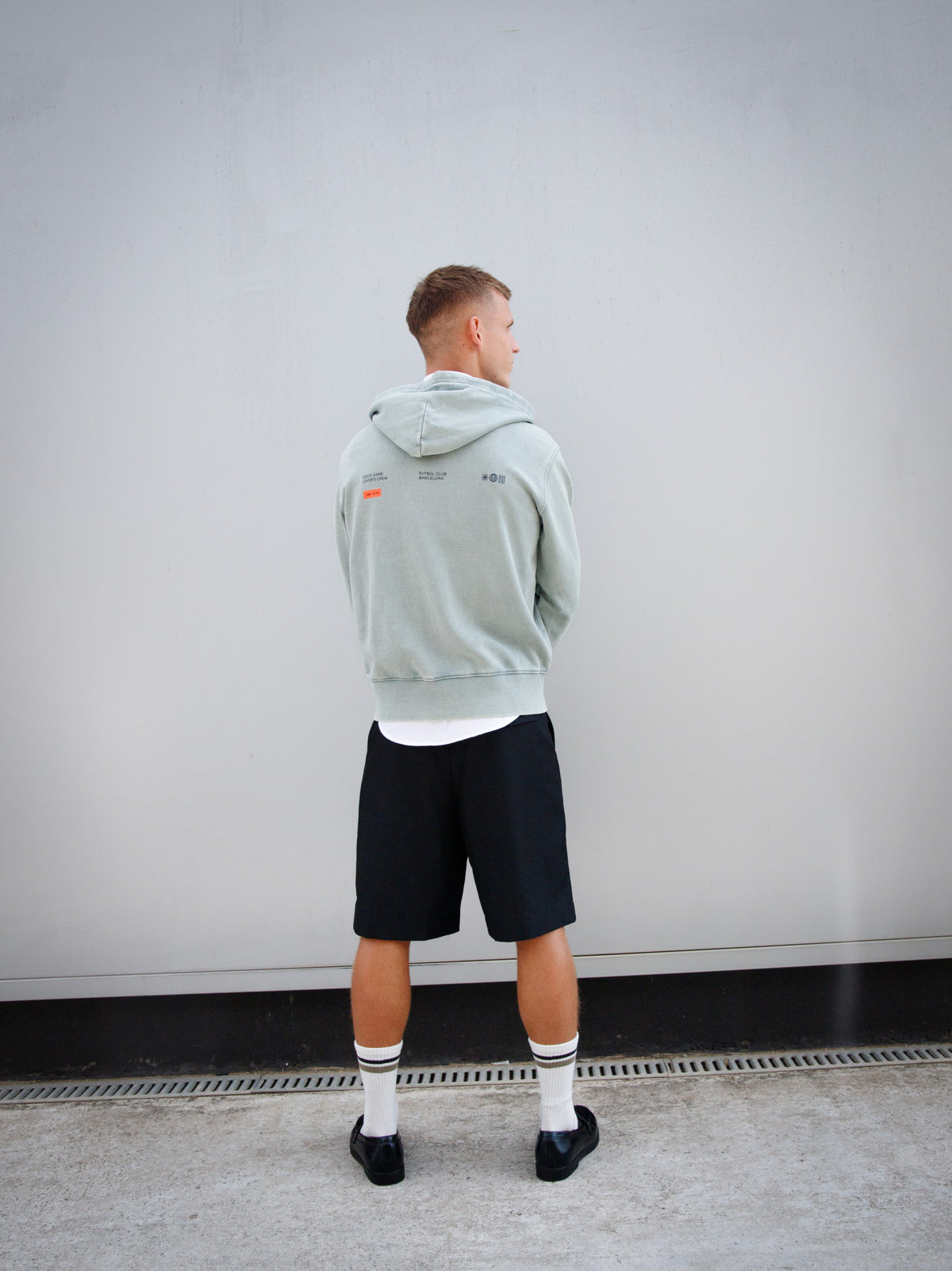 Dani Olmo wearing a light green FC Barcelona zip-up hoodie with tonal crest, paired with a white shirt and black shorts.