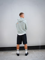 Dani Olmo wearing a light green FC Barcelona zip-up hoodie with tonal crest, paired with a white shirt and black shorts.