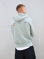 Dani Olmo wearing a light green FC Barcelona zip-up hoodie with tonal crest, paired with a white shirt and black shorts.