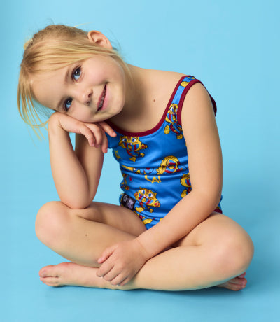 Two children wearing blue cartoon-themed ponchos on a solid background