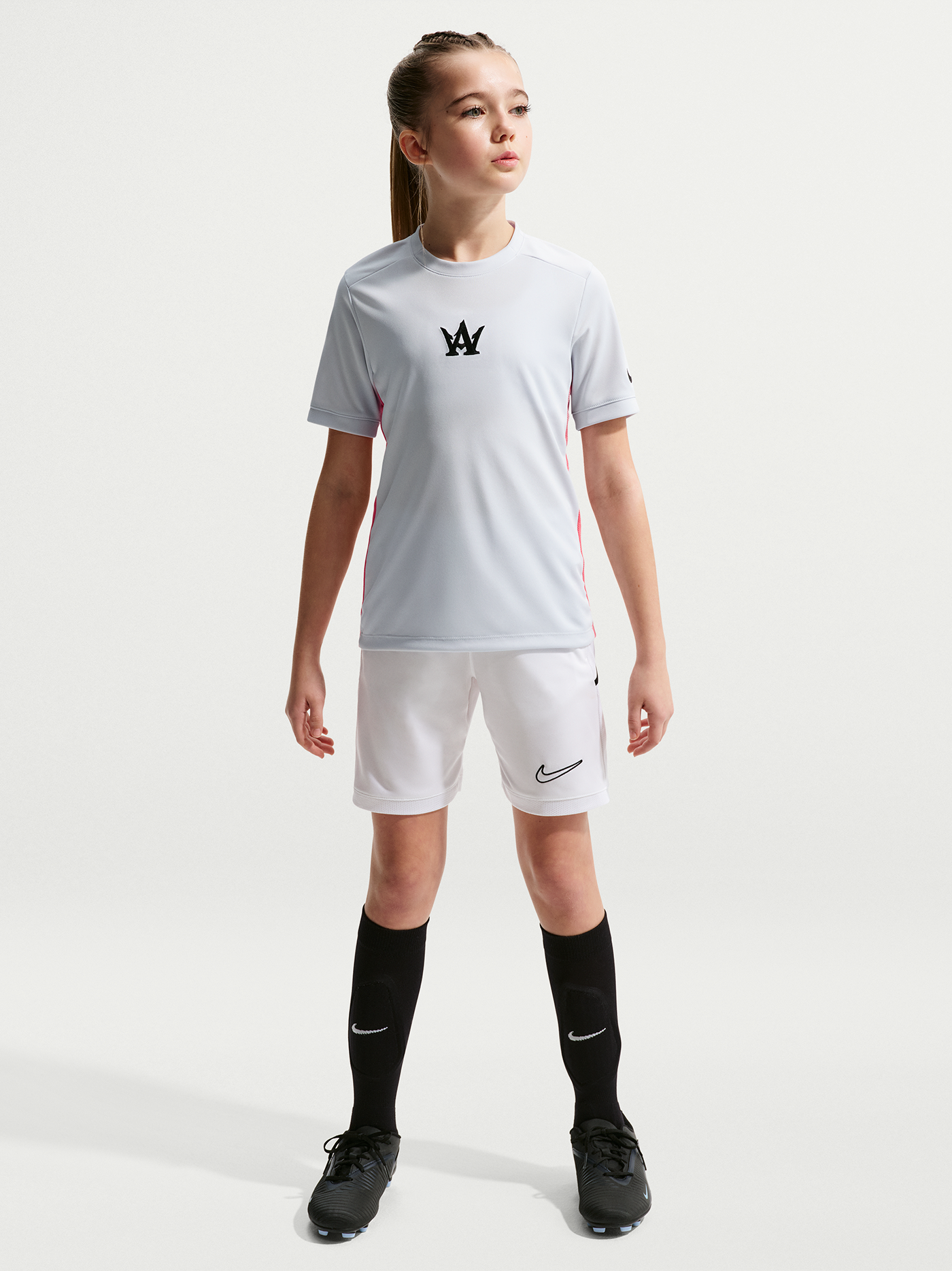 Young girl wearing a white sports outfit with a logo on a white background