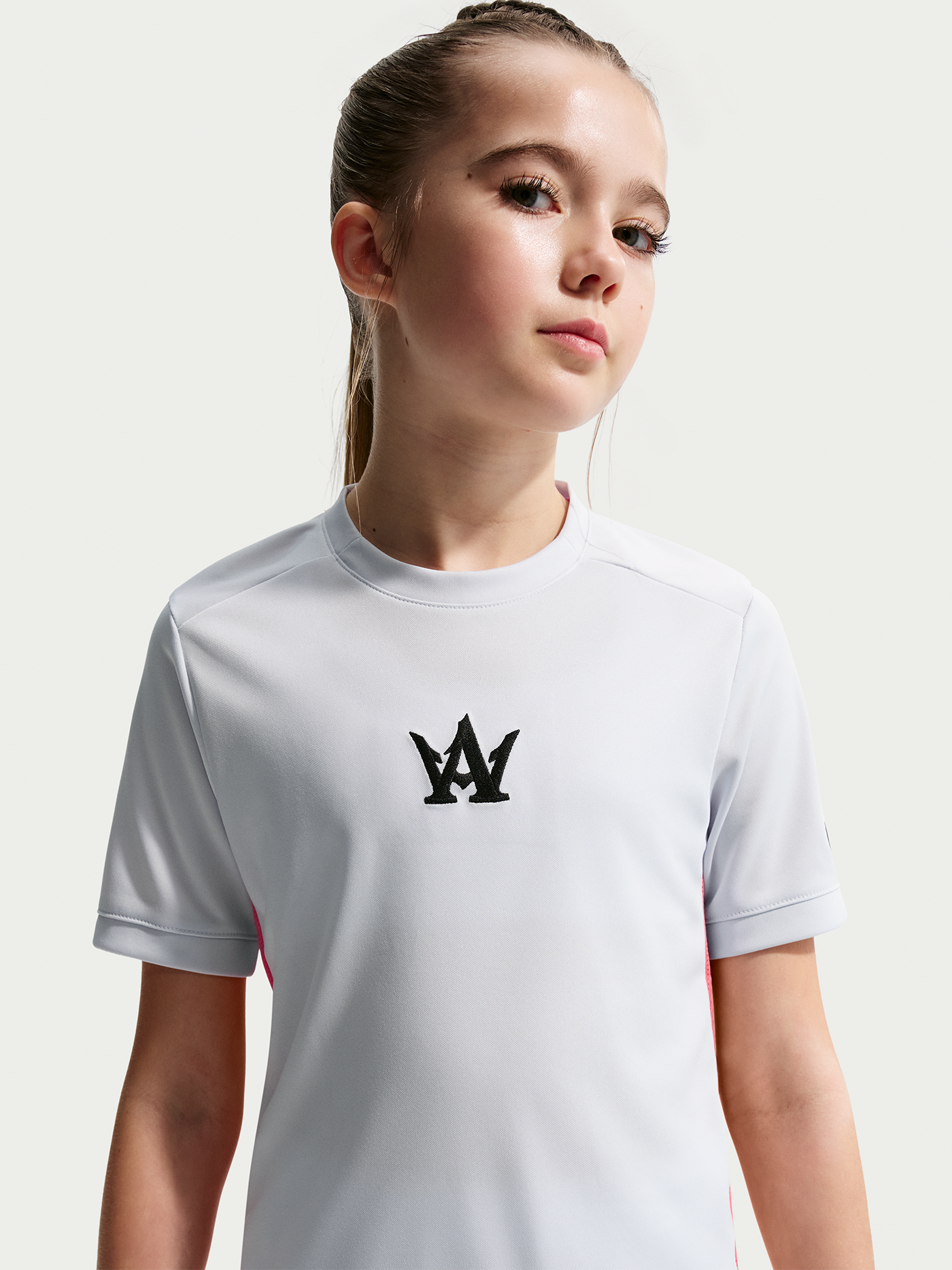 Young girl wearing a white t-shirt with a black logo on a light gray background