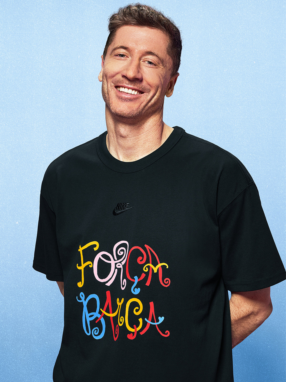 Man wearing a black t-shirt with colorful text on a light blue background