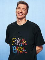 Man wearing a black t-shirt with colorful text on a light blue background