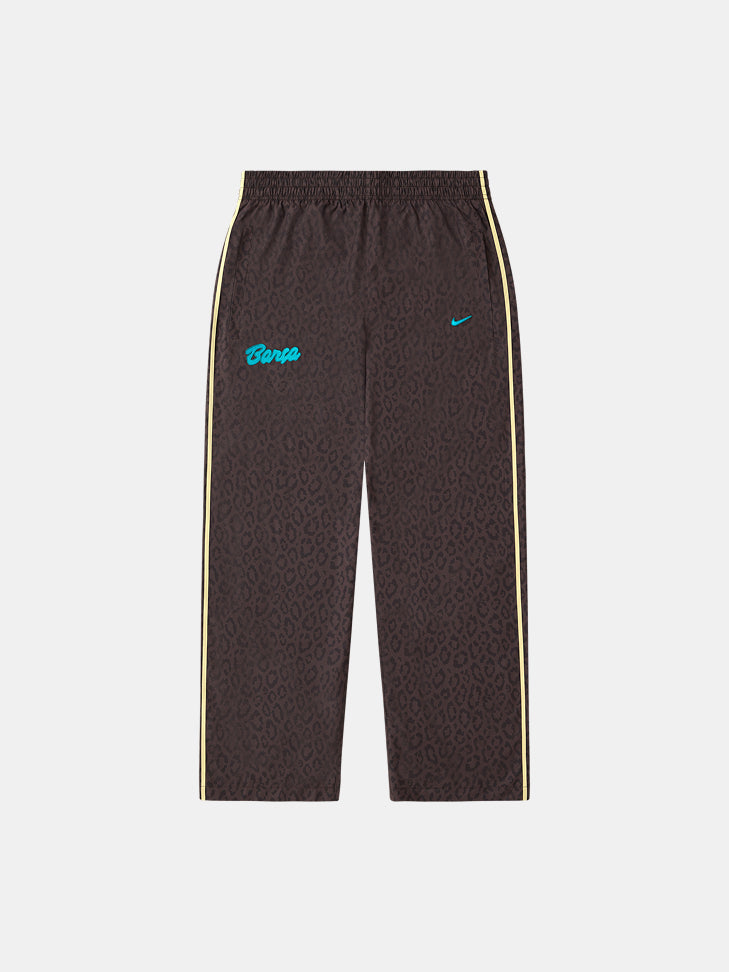Pantalón de chándal marrón con estampado de leopardo de FC Barcelona, con texto Barça en verde azulado, swoosh de Nike y franjas laterales claras.