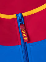 Détail d’une fermeture éclair bleue sur un vêtement FC Barcelona rouge et bleu avec passepoil jaune et étiquette pendante GOLF