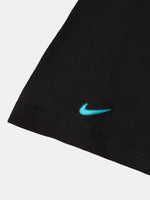 Détail du swoosh Nike turquoise sur l’ourlet d’un vêtement noir du FC Barcelona.