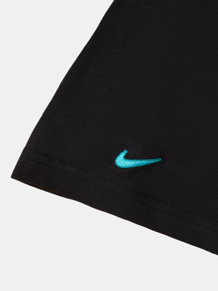 Détail du swoosh Nike turquoise sur l’ourlet d’un vêtement noir du FC Barcelona.
