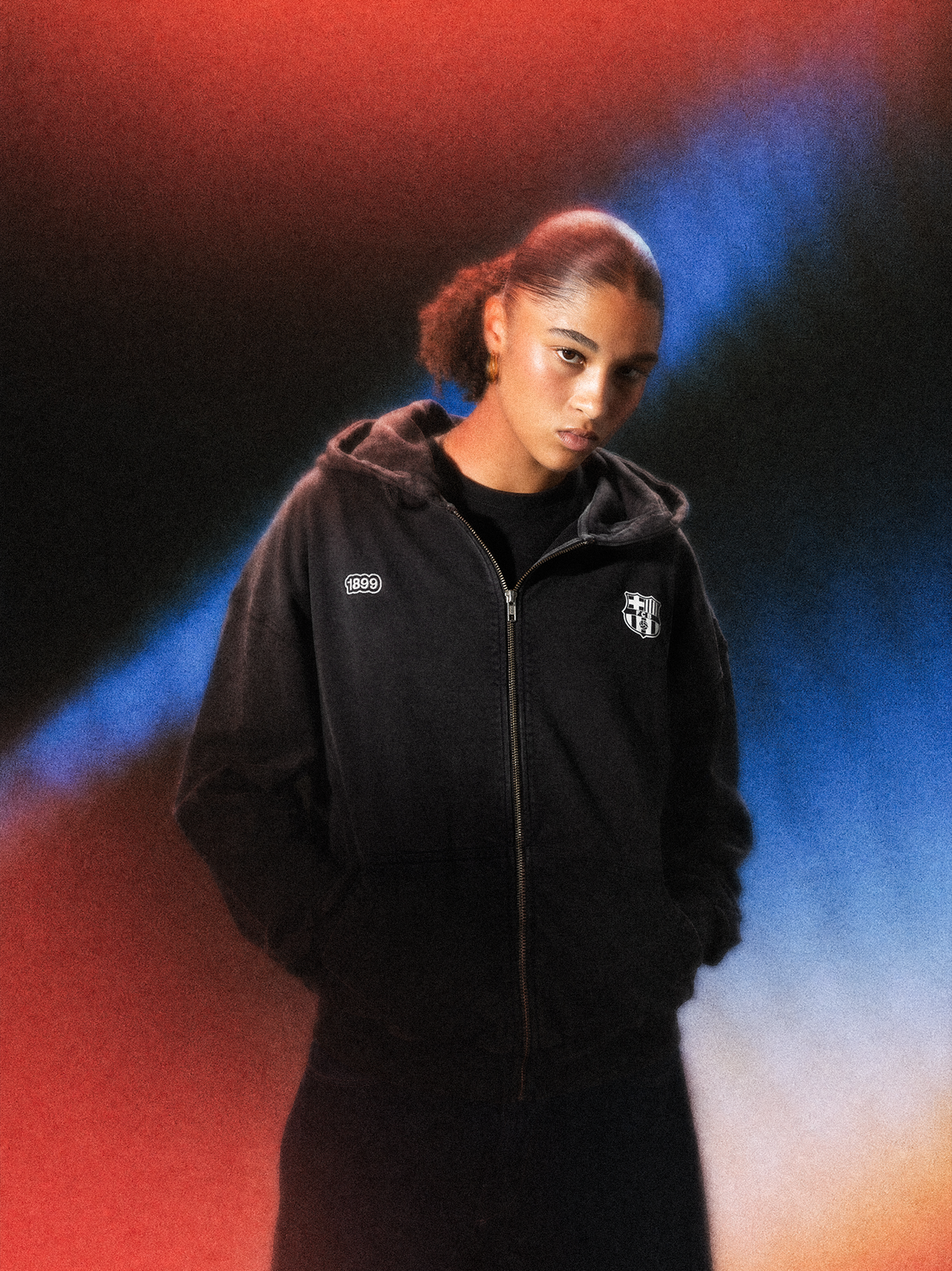 Vista frontal d’una dessuadora amb cremallera negra de FC Barcelona portada per un model, amb l’escut del Barça i 1899 estampats al pit.