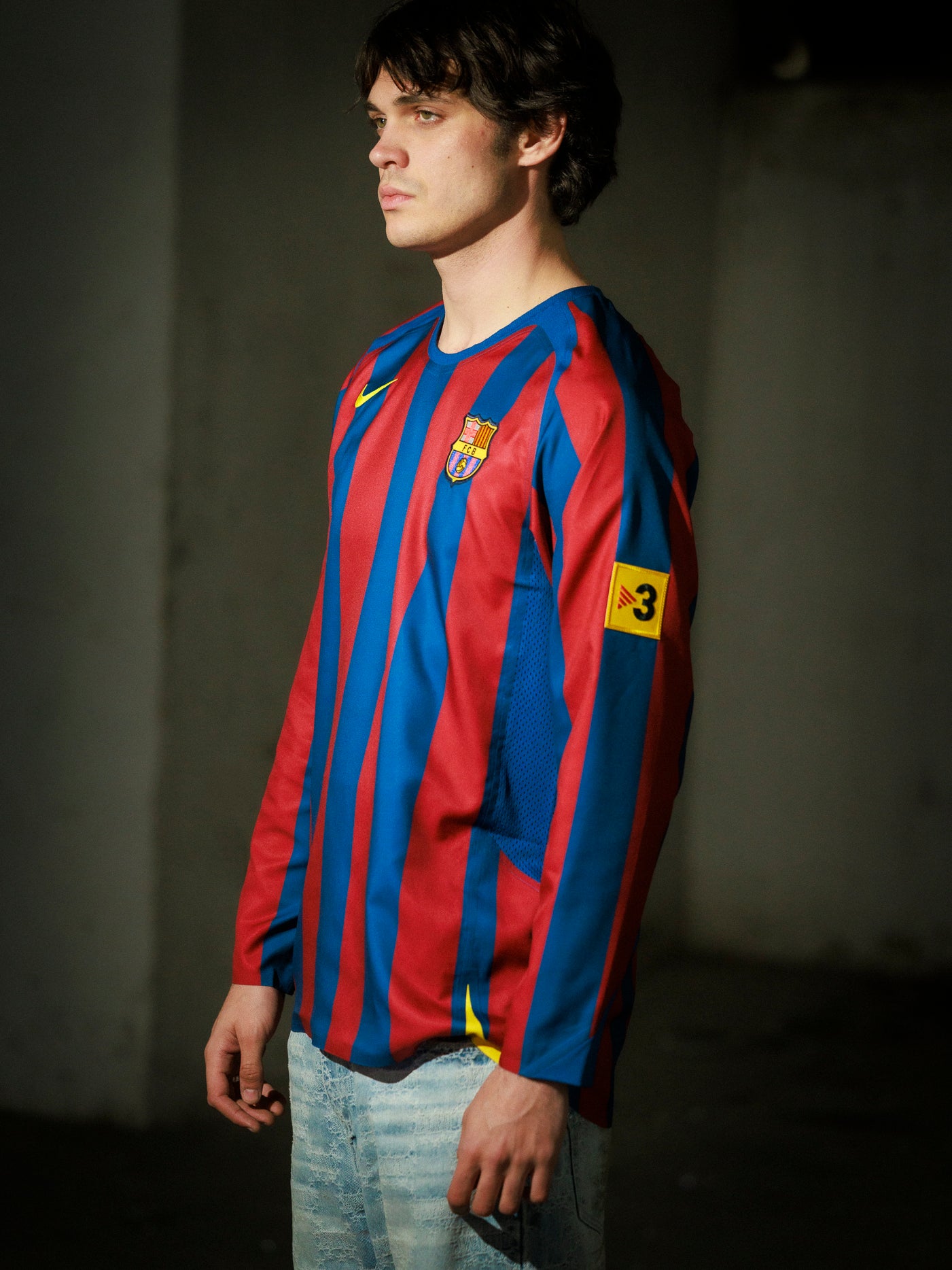 Person wearing a red and blue striped sports jersey with a logo on a dark background