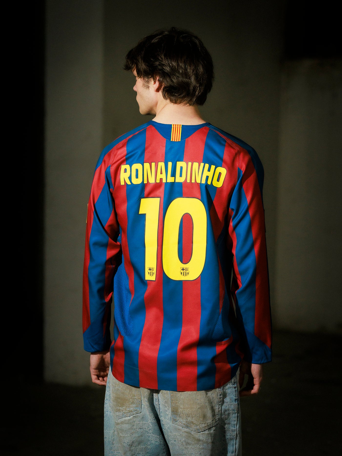 Person wearing a Barcelona jersey with 'Ronaldinho' and number '10' on a dark background