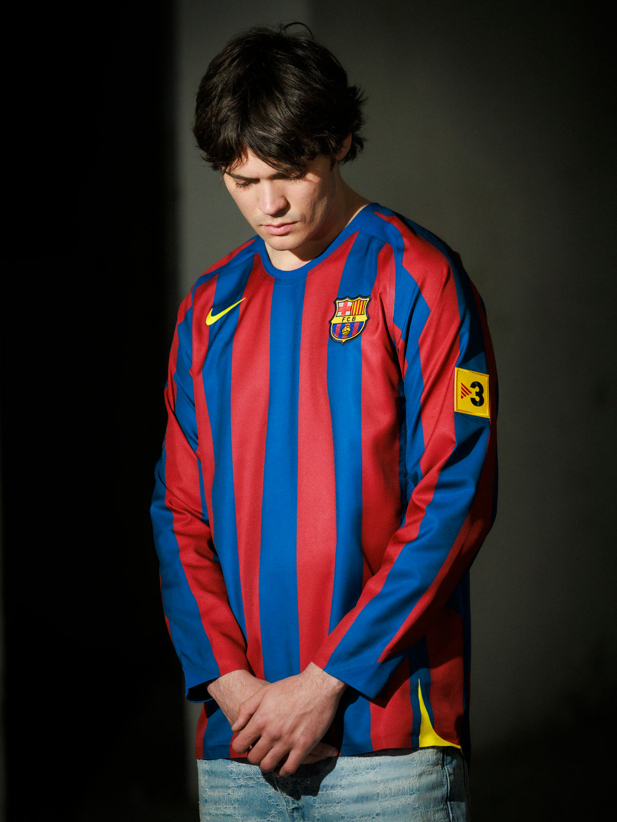 Person wearing a Barcelona football jersey with a dark background
