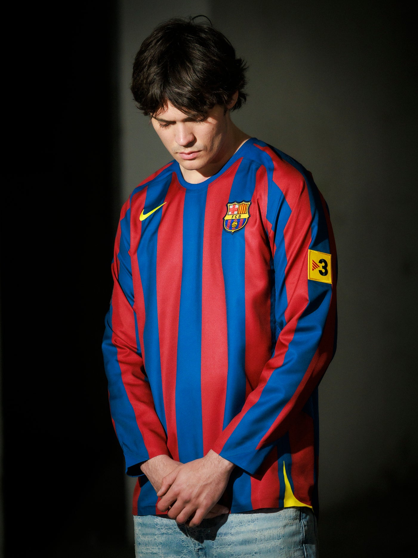 Person wearing a Barcelona football jersey with a dark background
