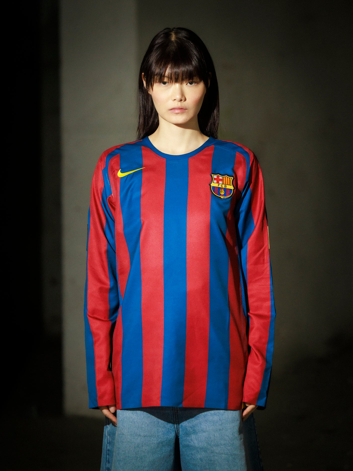 Person wearing a red and blue striped sports jersey with a logo on a dark background