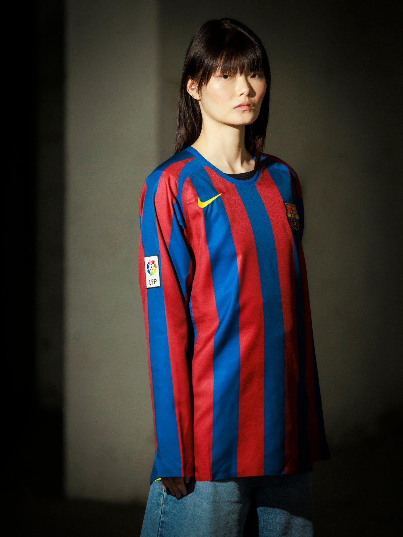 Person wearing a red and blue striped sports jersey with a logo on a dark background