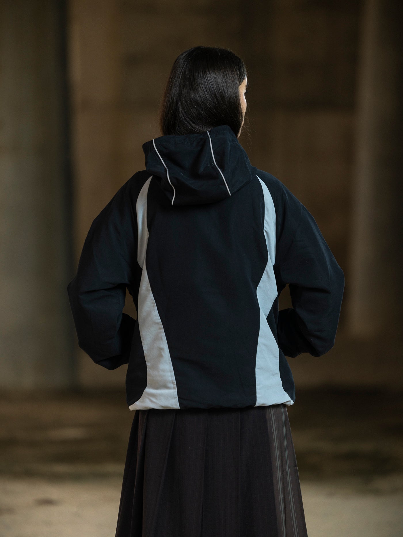 Person wearing a black and gray jacket in a dimly lit room