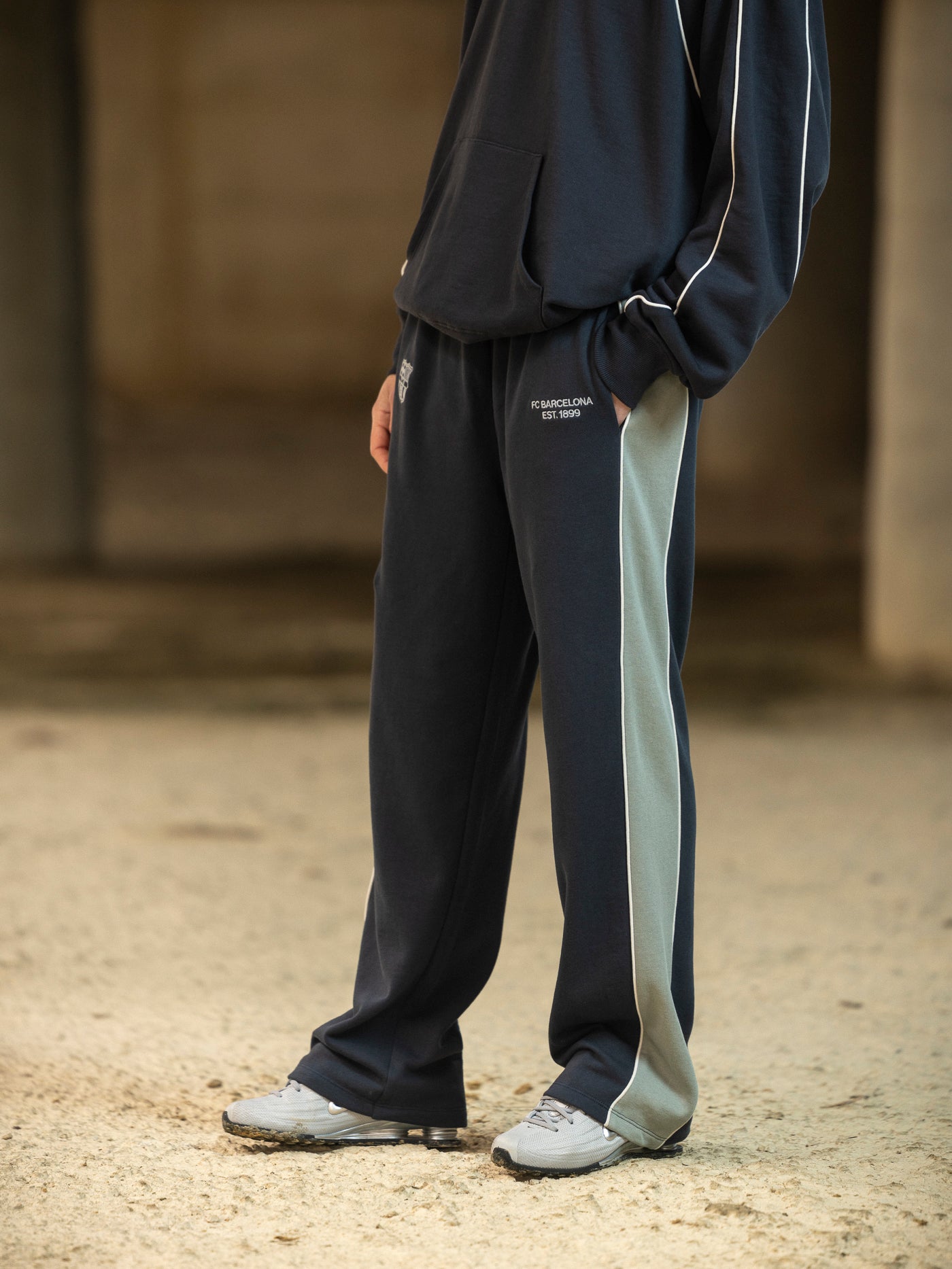 Person wearing a dark tracksuit with a light stripe on a blurred background