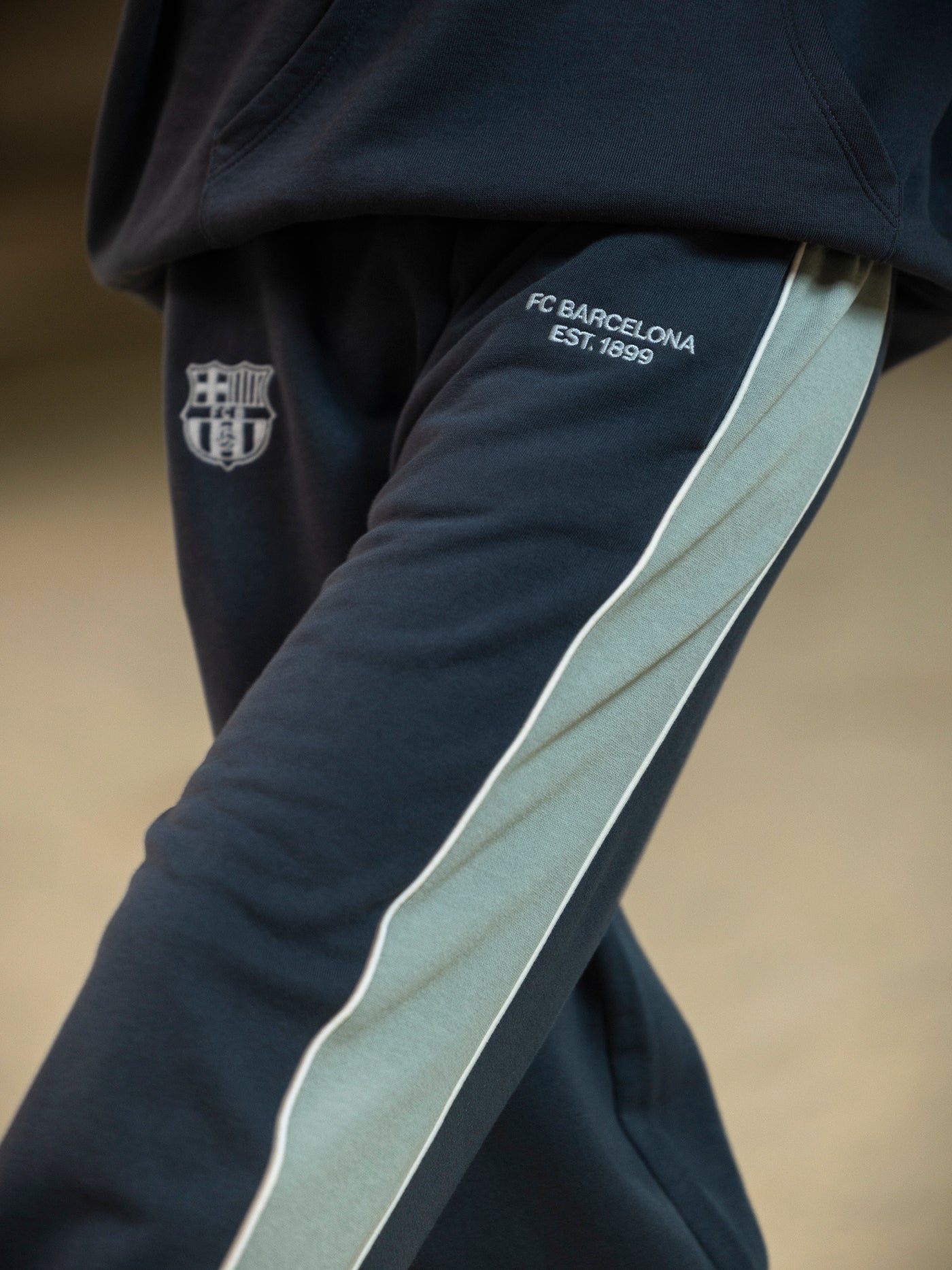 Navy blue sports pants with a logo and text on a beige background