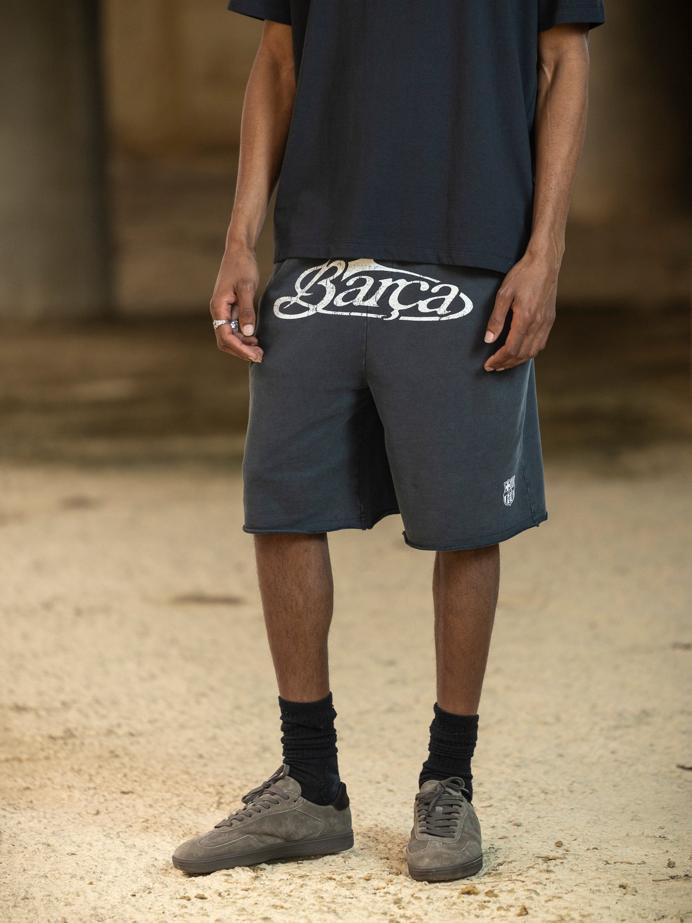 Person wearing dark shorts with 'Barca' branding on a blurred background