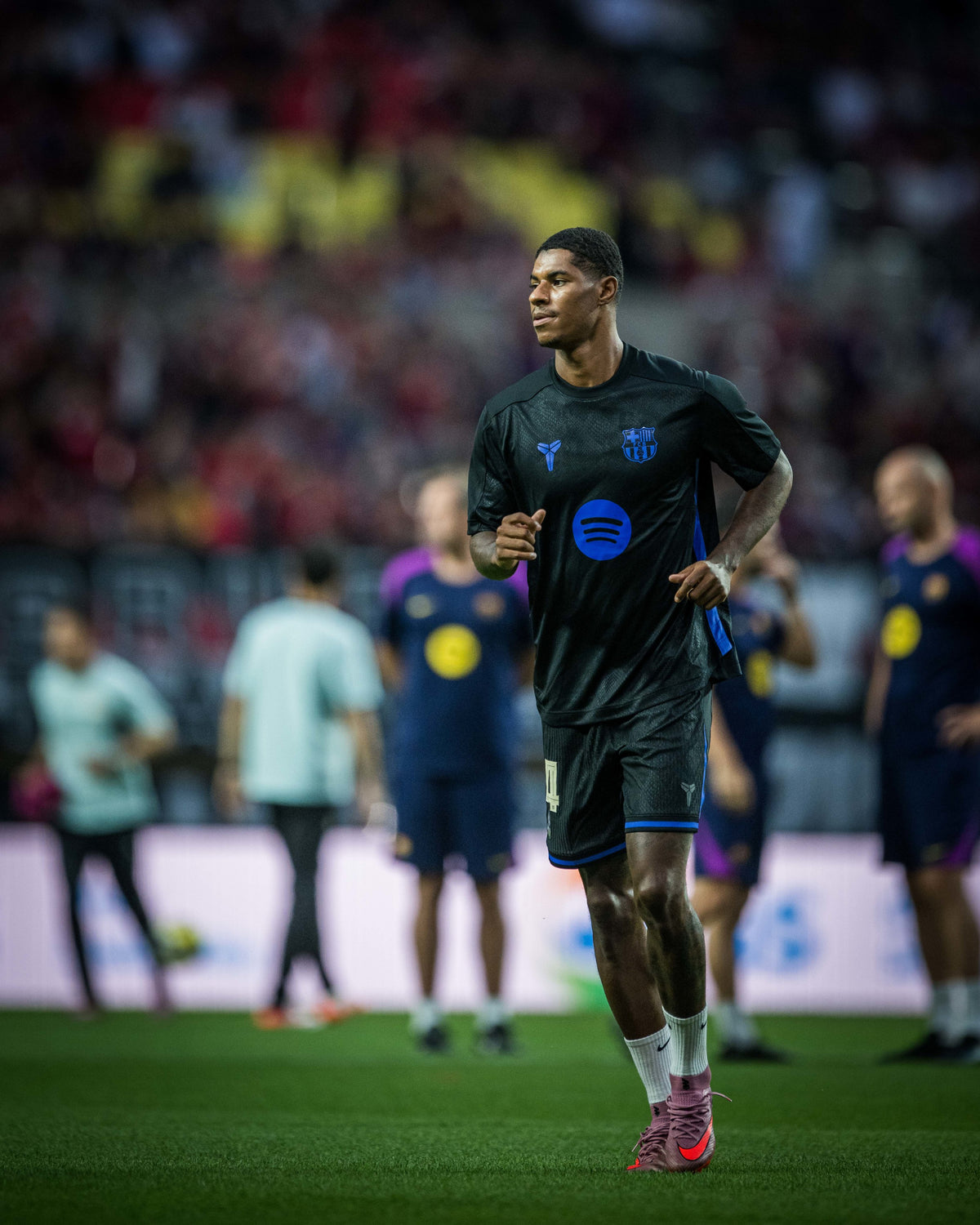 Marcus Rashford wearing a black FC Barcelona training kit with blue accents and Spotify sponsor logo during warm-up on the pitch