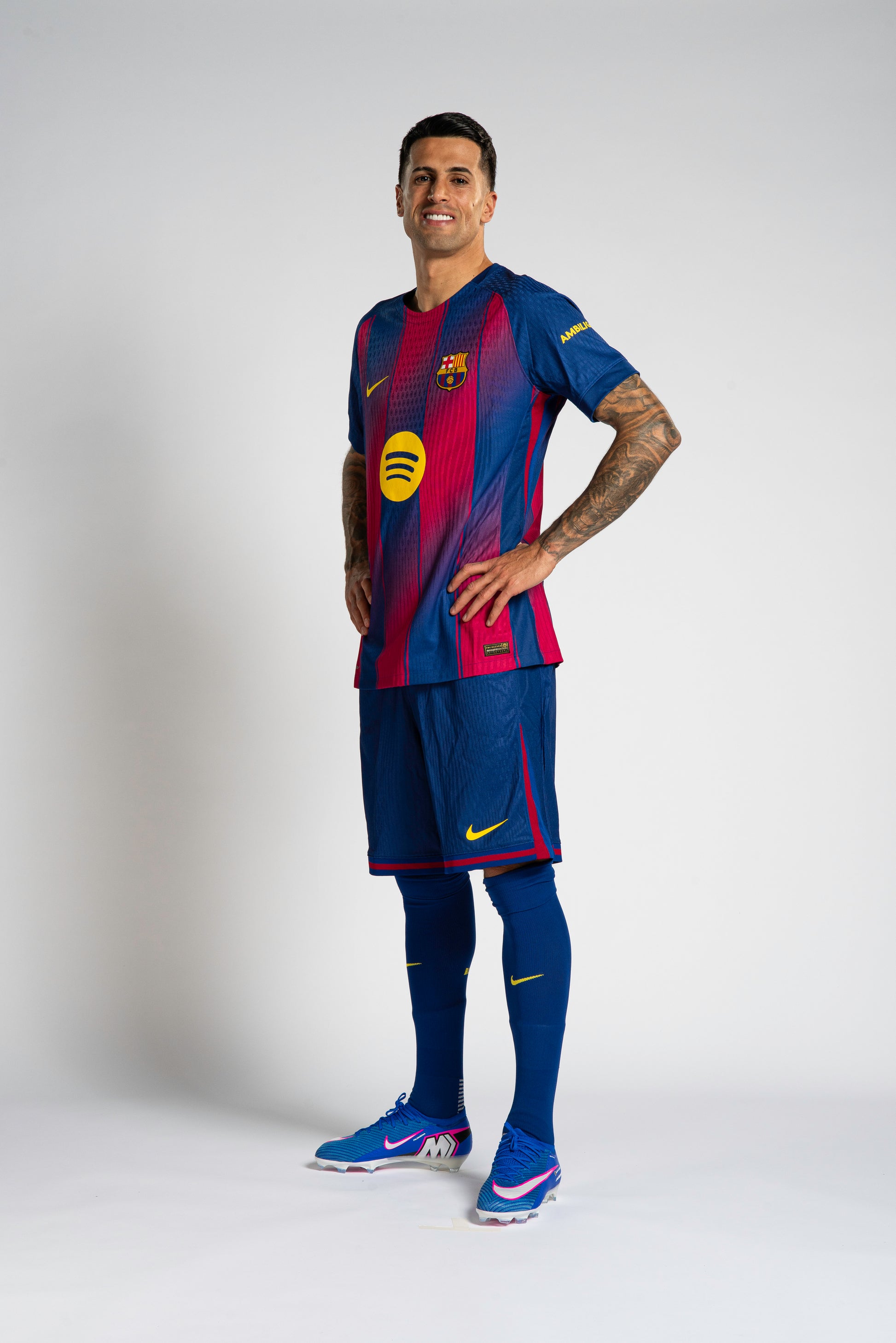 Cancelo wearing a Barcelona soccer jersey and shorts on a gray background